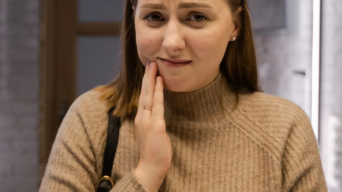 Douleur dentaire : une femme se tient la joue, signe possible d'un abcès