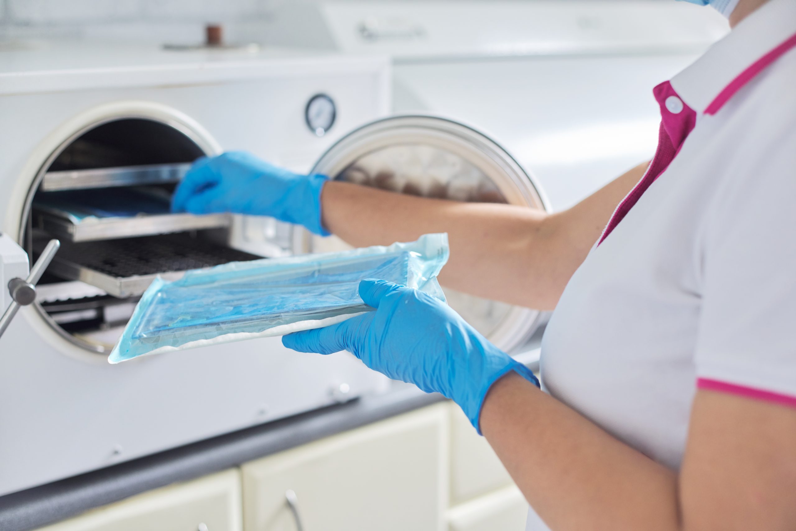 Female nurse doing sterilization of dental medical instruments in autoclave. Sterilization department at dental clinic